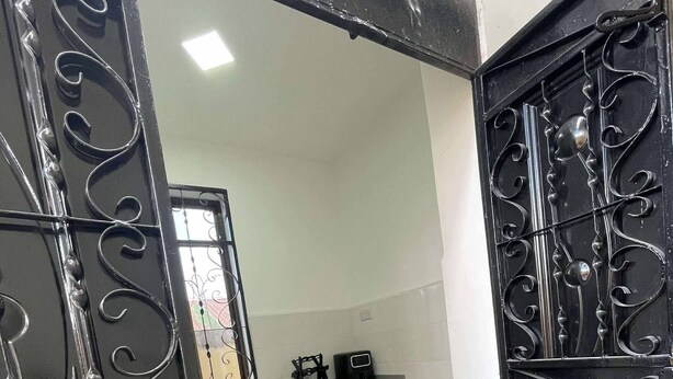 A kitchen with a black tiled floor, grey cabinets, and a black decorative gate. - Cozy Studio Near City & Masaki (Dar es Salaam)