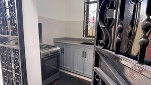 A kitchen with a gas stove, oven, and cabinets. - Cozy Studio Near City & Masaki (Dar es Salaam)