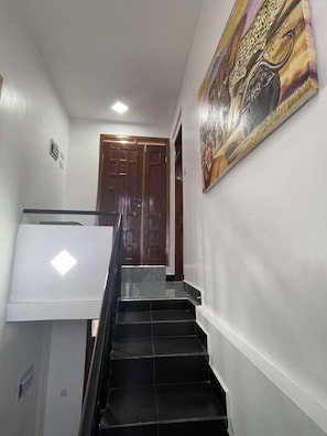 A staircase with a handrail, a door at the top, and a painting on the wall. - Cozy Studio Near City & Masaki (Dar es Salaam)