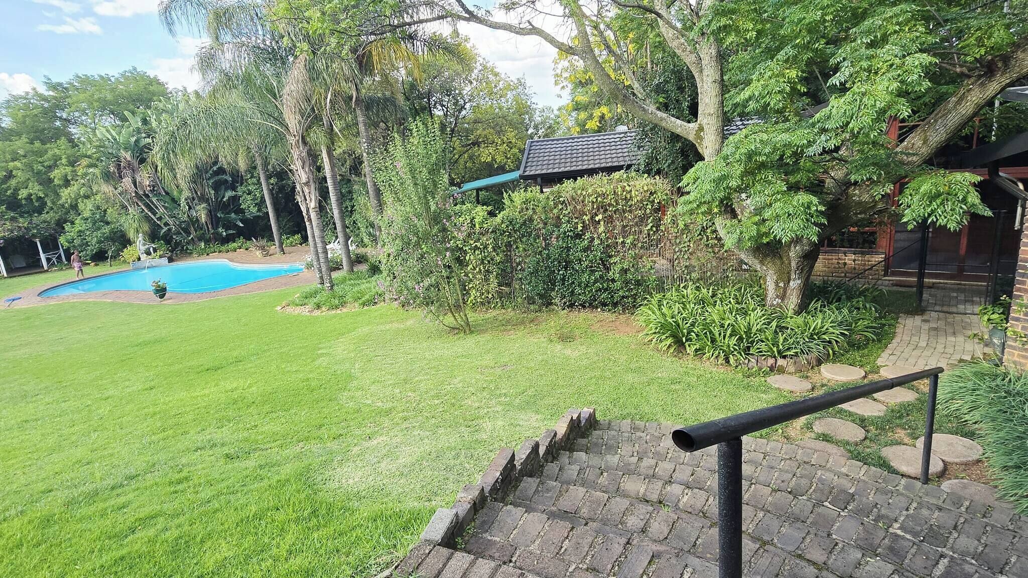 A well-maintained backyard with a swimming pool, a brick staircase, and lush greenery.
