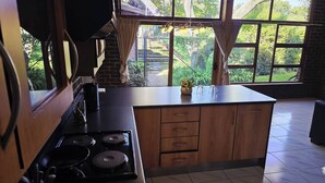 A kitchen with a stove, cabinets, and a window with curtains.
