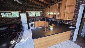 A compact kitchen with a central island, wooden cabinets, a built-in microwave, and a refrigerator.