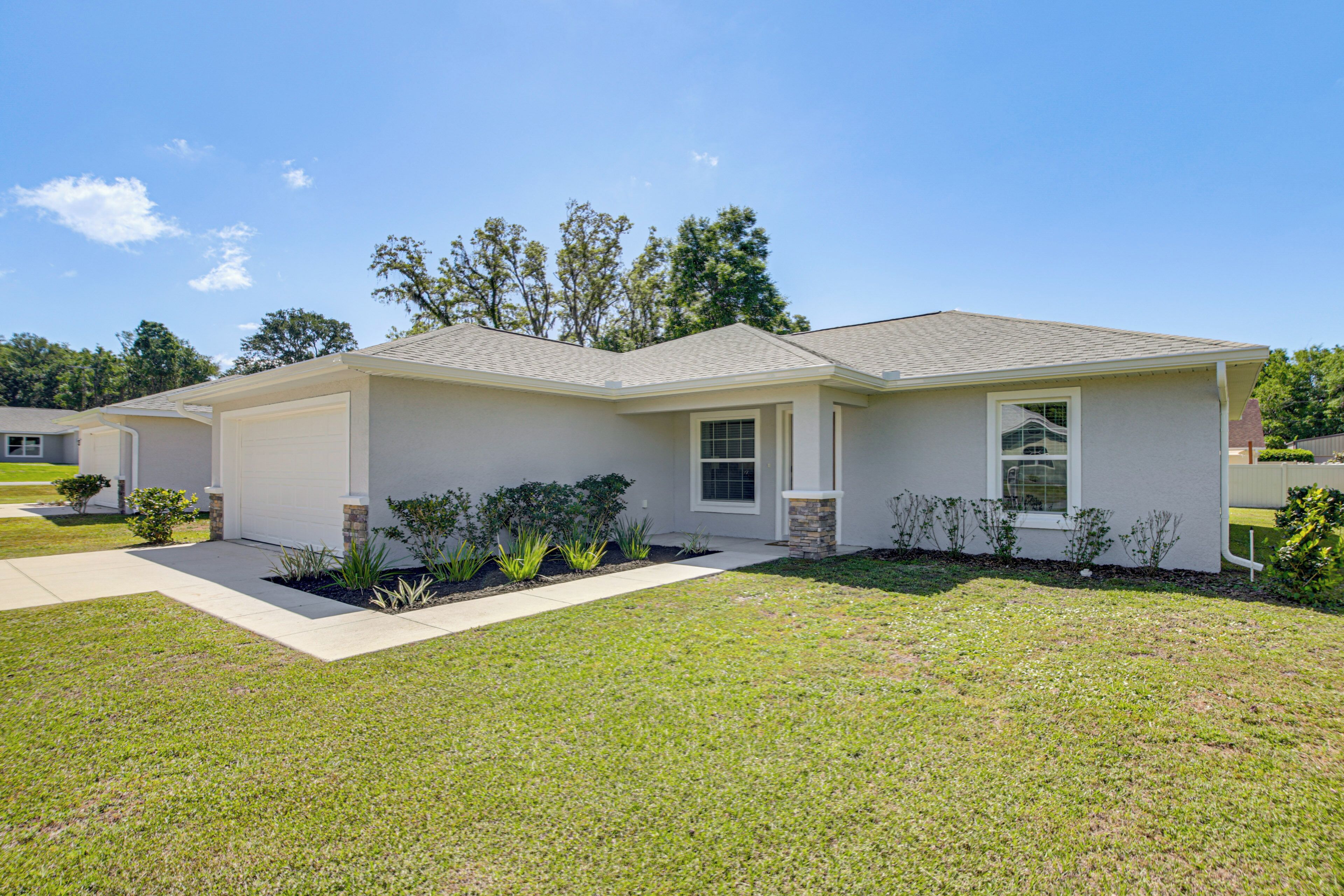 A single-story house with a garage, a front lawn, and a small garden area.