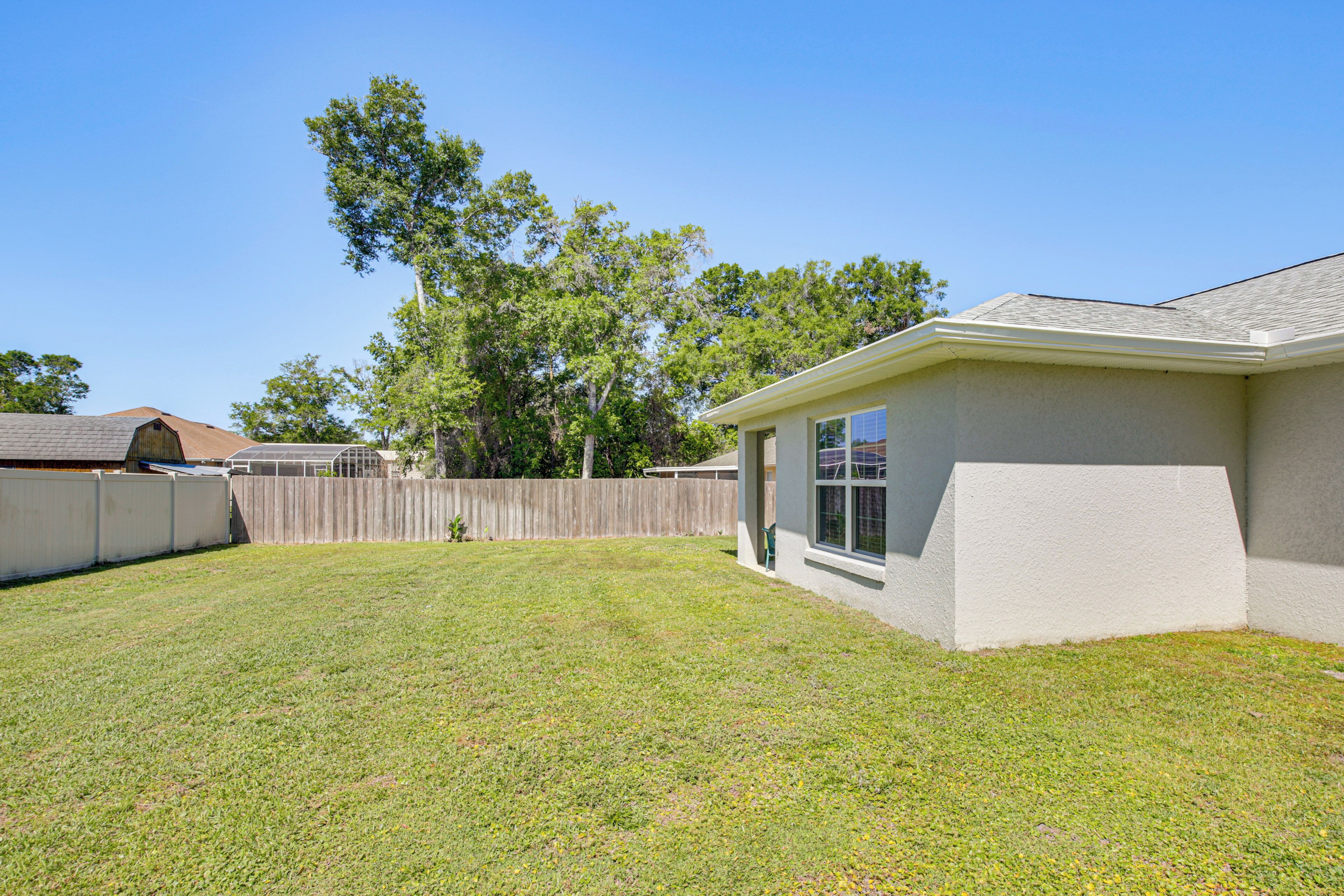 A residential backyard with a house, a wooden fence, and trees.