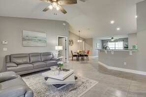 Un salon moderne avec un canapé gris, une table basse et un coin repas comprenant des chaises et une table.