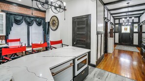 Cozinha com ilha de mármore, cadeiras vermelhas, relógio e luminária em formato de bicicleta.
