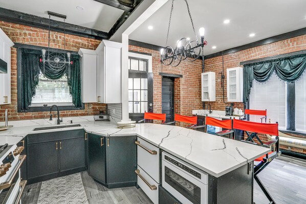A kitchen with a marble island, black and white cabinetry, and a brick wall. - Walkable Schenectady Getaway: 2-Unit Campus Hub (Schenectady)