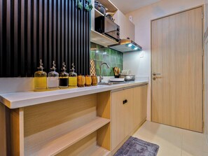 A modern kitchen with a wooden countertop, built-in cabinets, and a black vertical panel. - Forest-Themed Cozy Studio Near IT Park Cebu (Cebu City)