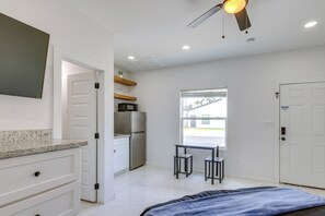 Ein Schlafzimmer mit Bett, Schreibtisch, Kühlschrank und Fenster.
