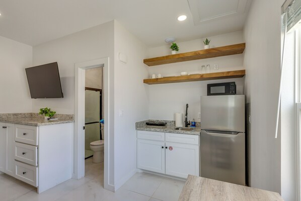 A modern kitchen with white cabinetry, a built-in microwave, and a stainless steel refrigerator. - Easy South Padre Beach Retreat w/ Pool Access (South Padre Island)