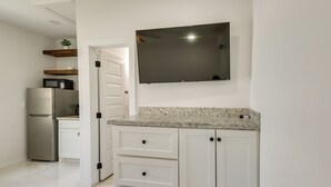 Eine Küche mit weißen Schränken, einer Granit Arbeitsplatte, einer Mikrowelle und einem Kühlschrank.