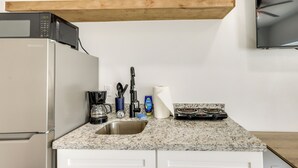 Une cuisine équipée d’un four à micro-ondes, d’une machine à café, d’un évier et d’une cuisinière.