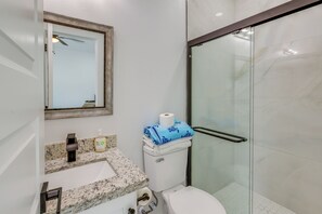 A bathroom with a marble sink, a toilet, a glass shower enclosure, and a mirror with a wooden frame. - Central to Everything, Easy Beach Access! SPI Stay (South Padre Island)