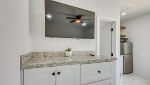 A kitchen with a granite countertop, white cabinets, a built-in oven, and a refrigerator. - Beach Base for Groups! SPI Studio w/ Pool On-Site (South Padre Island)