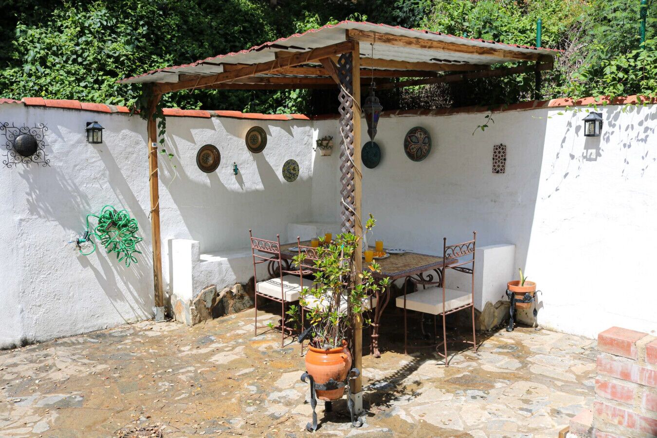 A patio with a table and chairs, a pergola, and potted plants.