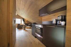 A modern kitchen with wooden walls, a built-in oven, and a coffee maker. - Alpine Stay, Sauna & Fireplace (Bramberg am Wildkogel)