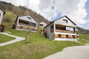A modern chalet with a stone facade, wooden balconies, and a gravel driveway. - Alpine Stay, Sauna & Fireplace (Bramberg am Wildkogel)
