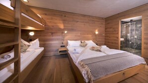 A wooden room with bunk beds, a glass shower, and a small bedside table with a lamp. - Alpine Stay, Sauna & Fireplace (Bramberg am Wildkogel)