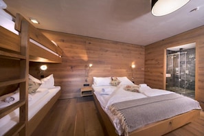 A wooden room with bunk beds, a glass shower, and a small bedside table with a lamp. - Alpine Stay, Sauna & Fireplace (Bramberg am Wildkogel)