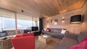 Un salon moderne avec un canapé, un fauteuil rouge et une table basse.