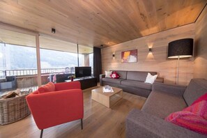 A modern living room with a sofa, red armchair, and a coffee table. - Alpine Stay, Sauna & Fireplace (Bramberg am Wildkogel)