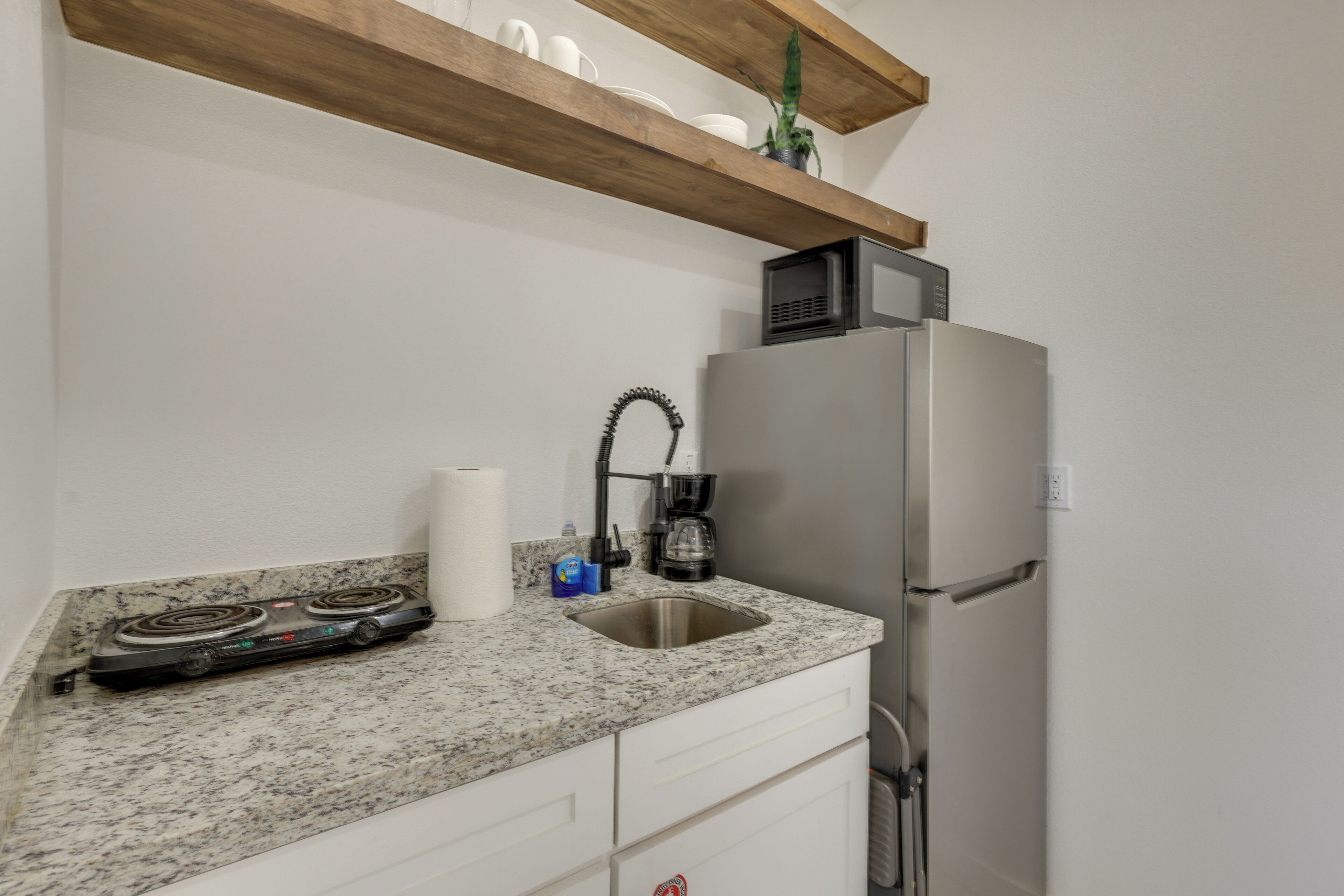 Une cuisine dotée d’un plan de travail en granit, d’appareils électroménagers en acier inoxydable, d’un four à micro-ondes et d’une machine à café.