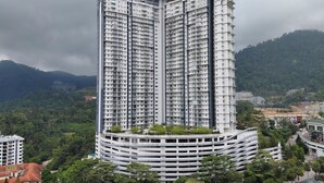 Un edificio alto con varios pisos, rodeado de vegetación y colinas.