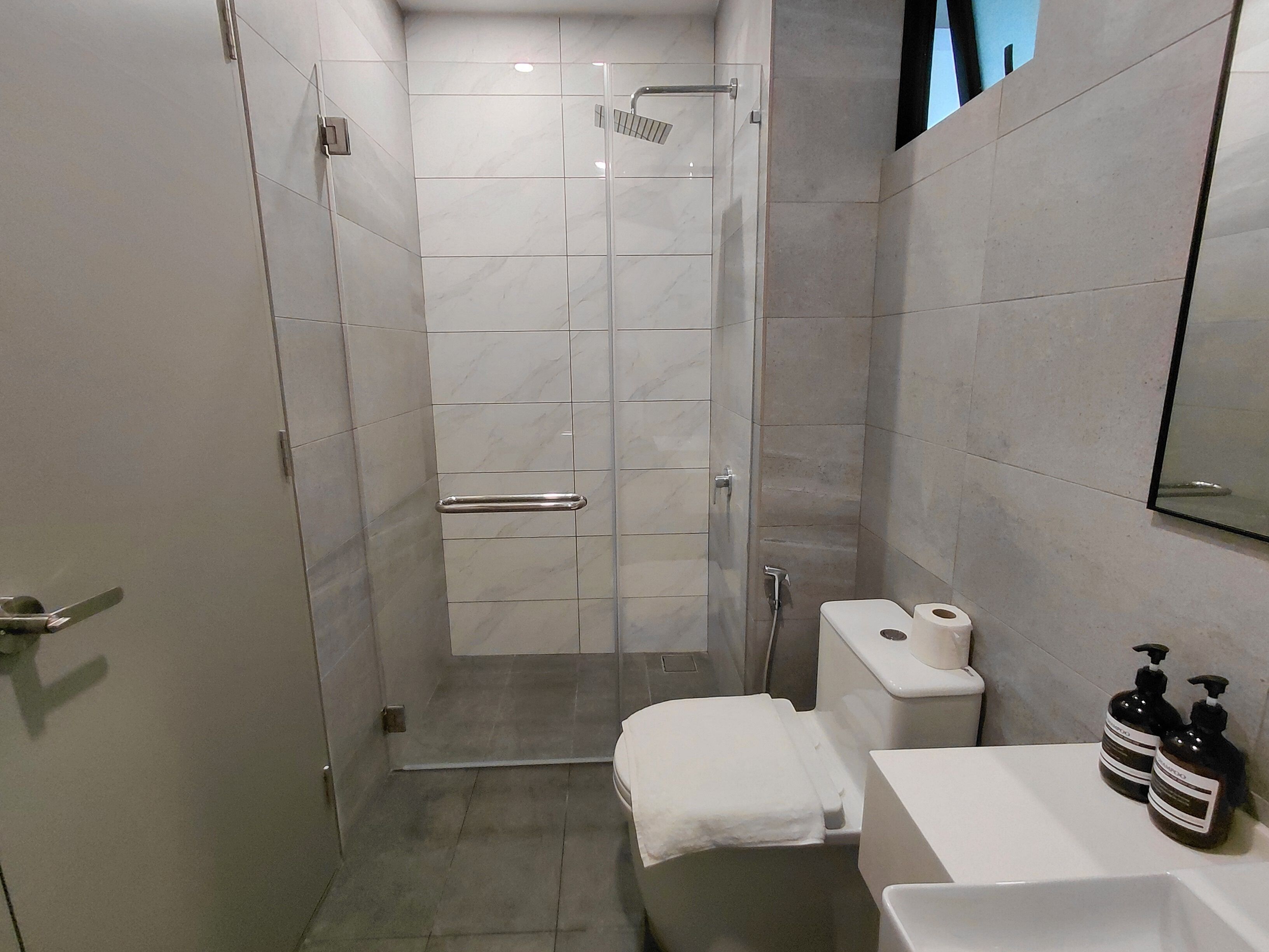 Une salle de bain moderne dotée d’une douche à parois de verre, de toilettes et d’un lavabo avec des articles de toilette.