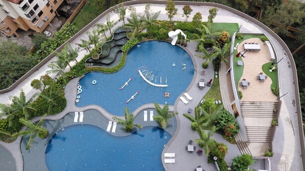 Una piscina de diseño singular, rodeada de zonas de descanso y vegetación.