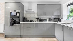 Eine moderne Küche mit grauen Schränken, einem eingebauten Backofen, einer Mikrowelle und einem Toaster.