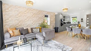 Ein modernes Wohnzimmer mit einer Eckcouch, einem Glastisch und einer Wand mit Marmoroptik.
