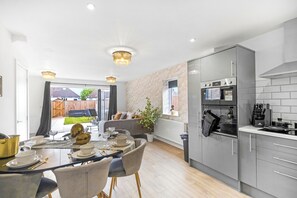 A modern kitchen with grey cabinets, a built-in oven, and a dining area with a table set for four.
