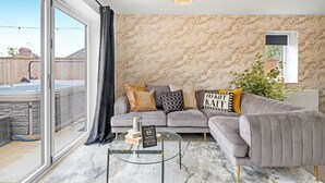 Ein Wohnzimmer mit grauem Sofa, einem Glastisch und einer Wand mit Marmoroptik.