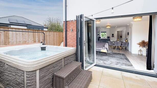 Ein modernes Haus mit Whirlpool, Essbereich und durch Glastüren einsehbarer Küche.