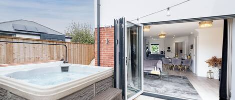 Una casa moderna con un jacuzzi, un comedor y una cocina visibles a través de puertas de vidrio.