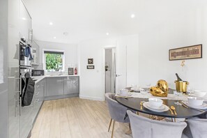 A modern kitchen with a dining area, a view of greenery outside, and a framed sign on the wall.