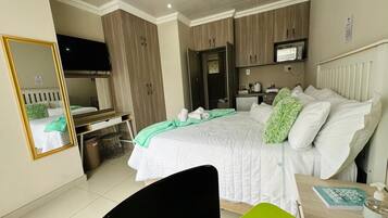 A bedroom with a bed, bedside table, mirror, and a desk with a chair.