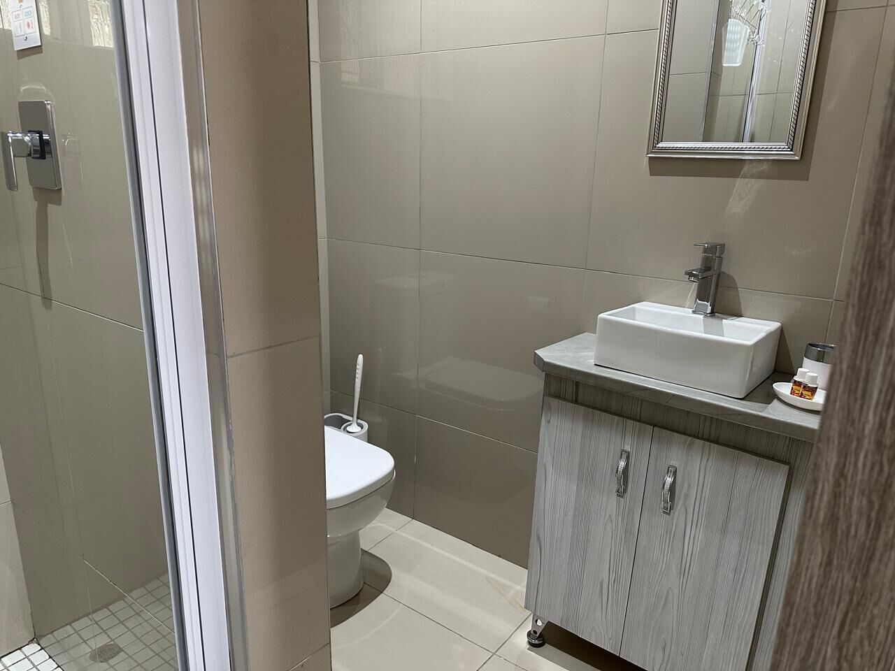 A bathroom with a toilet, a sink, and a mirror.