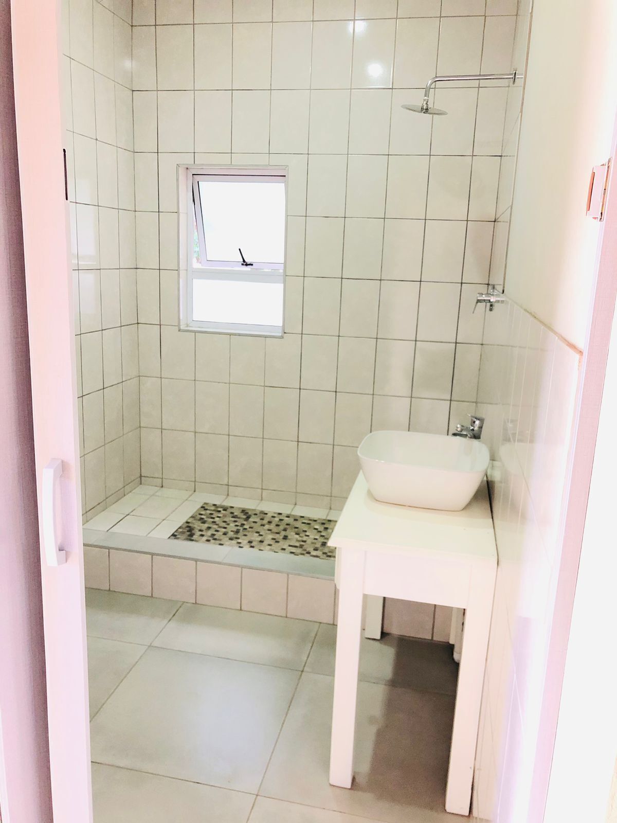 Un bagno con doccia, una finestra e un lavandino.