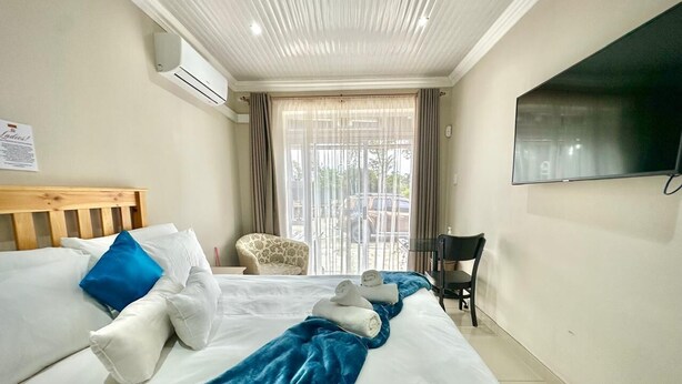 A hotel room with two beds, a TV, a chair, and a balcony with a view. - Arise Boutique Guesthouse (KuGompo City)