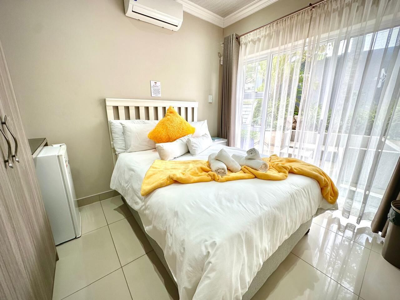 A hotel room with a bed, a white radiator, and a window with curtains.