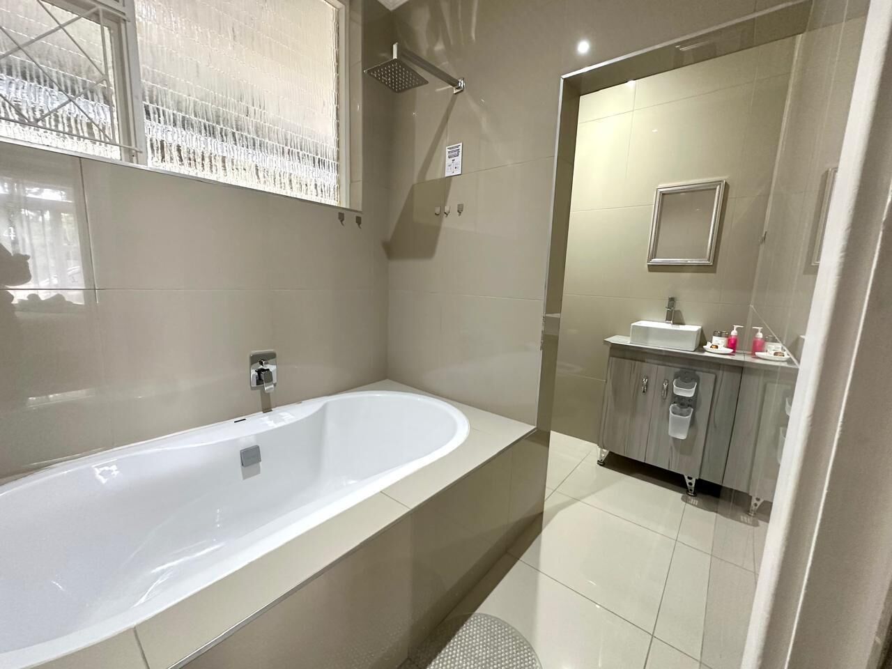 A modern bathroom with a freestanding bathtub, a showerhead, and a vanity with a sink and mirror.