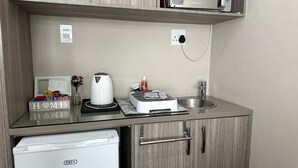 A compact kitchenette with a microwave, kettle, and small refrigerator. - Arise Boutique Guesthouse (KuGompo City)