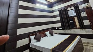 Un dormitorio moderno con cama, ventilador de techo y diseño de pared a rayas.