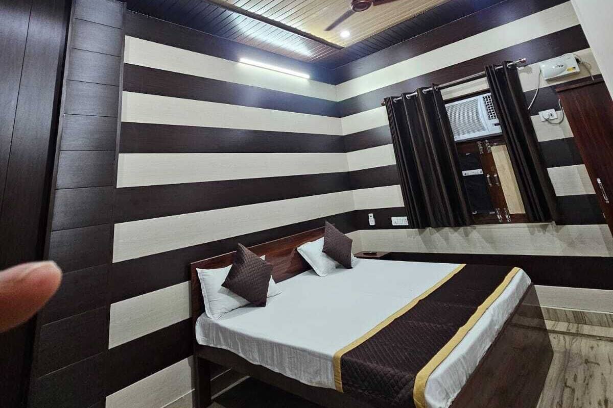 Une chambre moderne avec un lit, un ventilateur de plafond et un motif rayé sur un des murs.