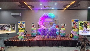 Un escenario decorado para un cumpleaños, con globos y recortes de personajes de Disney.