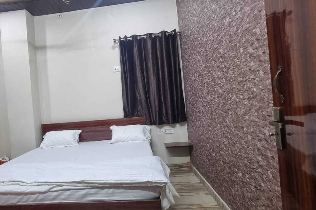 Une chambre à coucher avec un lit, une porte en bois, un mur à motifs et un rideau.