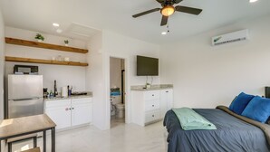 Ein modernes Schlafzimmer mit Bett, Schreibtisch, Küchenzeile und Deckenventilator.