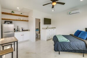 A modern bedroom with a bed, a desk, a kitchenette, and a ceiling fan. - Walkable & Modern! South Padre Studio By Beach (South Padre Island)