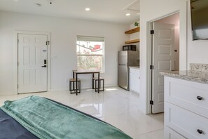 A kitchen with a refrigerator, microwave, and a window with a view of a red building. - Walkable & Modern! South Padre Studio By Beach (South Padre Island)
